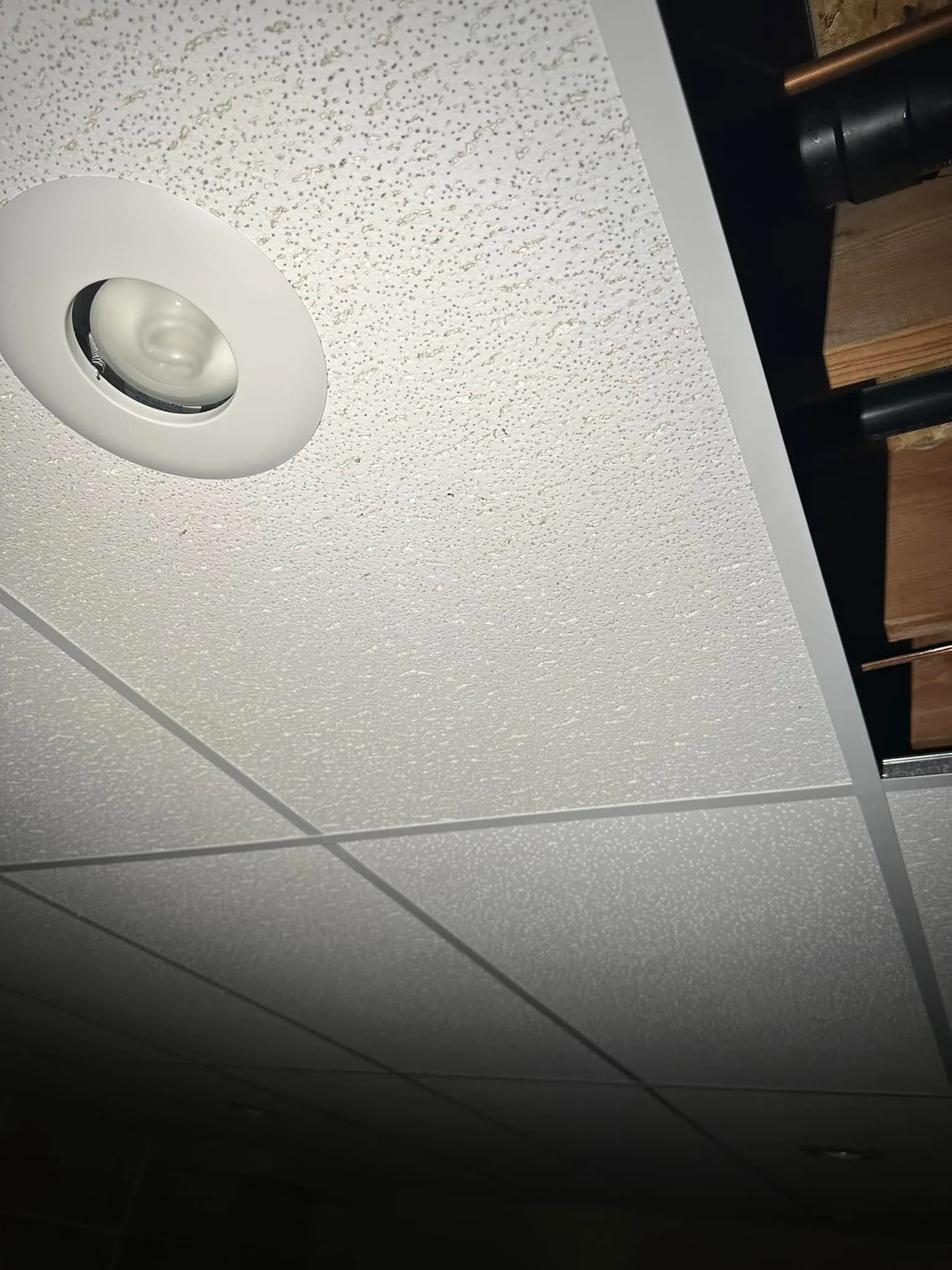 Drop ceiling tile missing recessed light exposed joists pipes