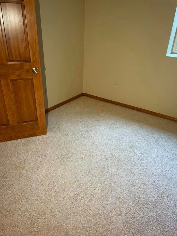 Empty bedroom beige carpet oak door stained trim