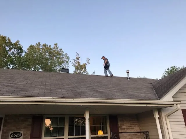 Inspector walking asphalt shingle roof ranch