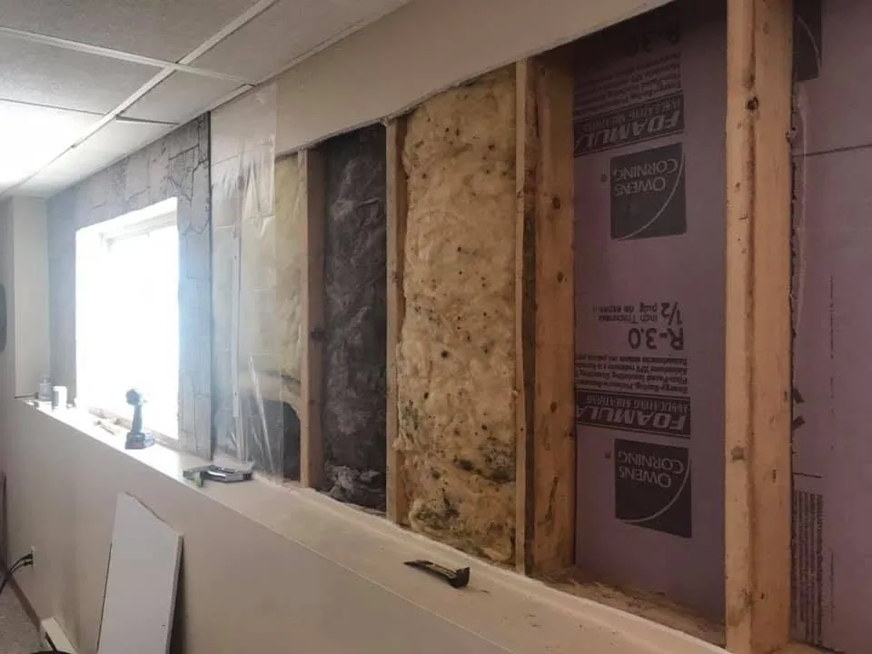 Opened basement wall studs foam board dirty fiberglass