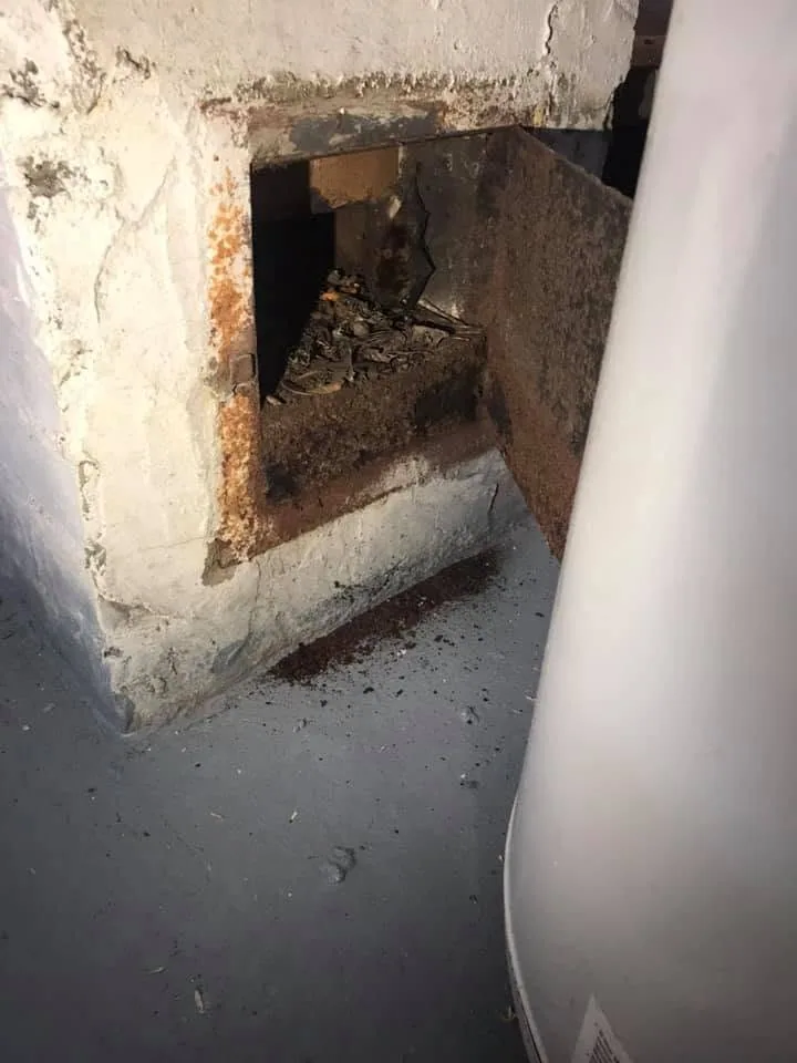 Rusted chimney cleanout door debris basement