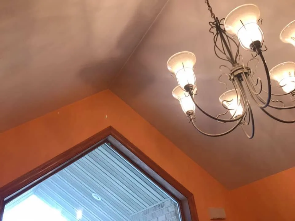 Vaulted ceiling chandelier orange walls angled window