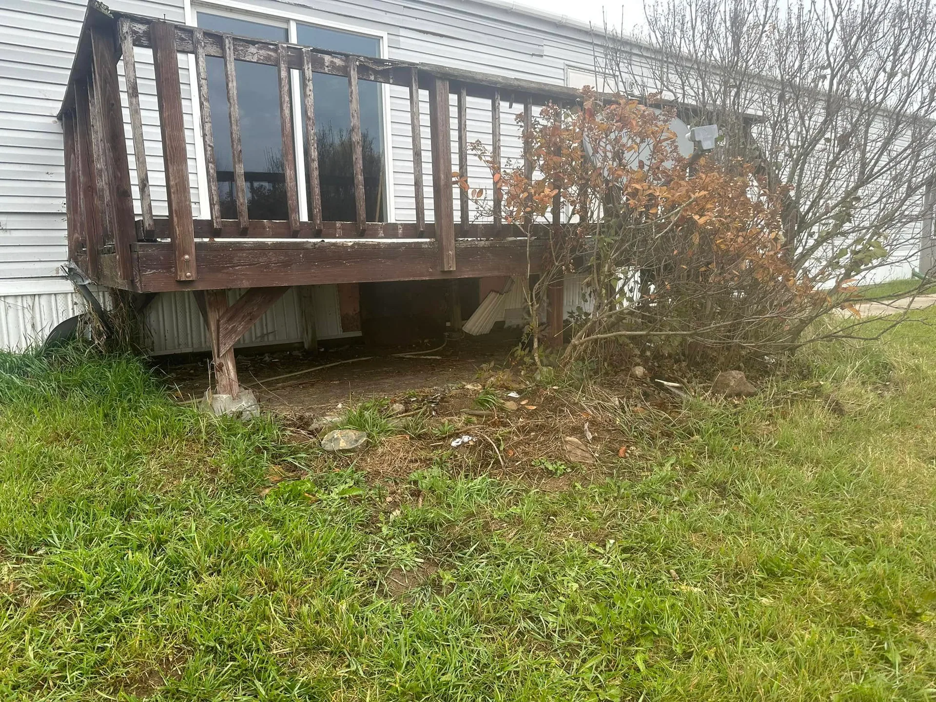 Weathered wood deck mobile home exposed posts debris underneath